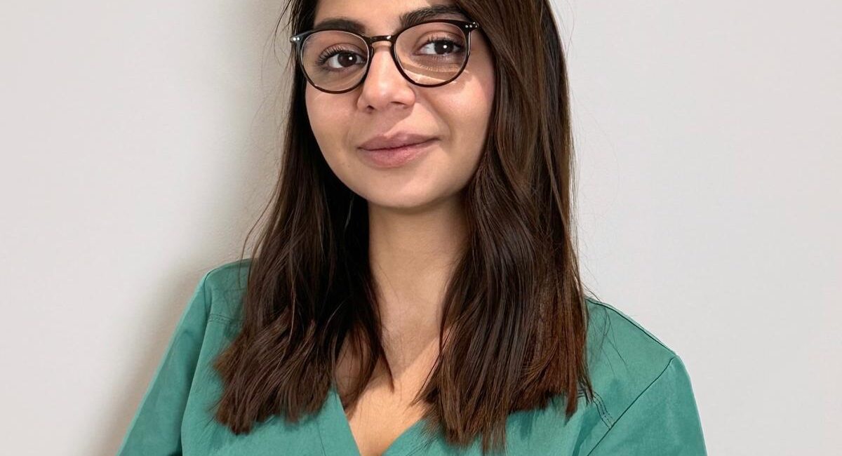 Auf dem Bild ist eine schwarzhaarige Frau zu sehen. Sie trägt eine Brille und lächelt in die Kamera. Ihr name ist Ionela